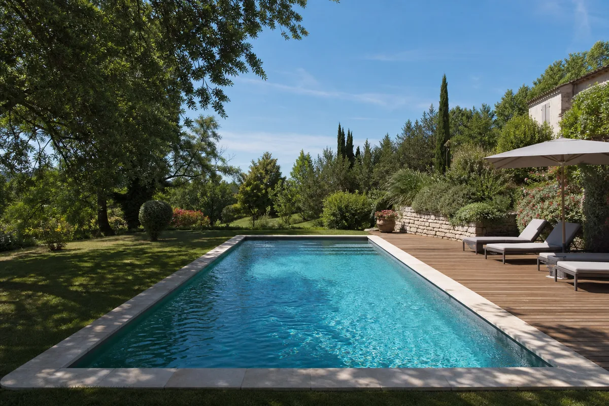 Belle piscine enterrée achevée dans un jardin du Tarn-et-Garonne, plage en bois et margelles claires sous le soleil du Sud-Ouest